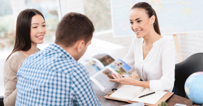 Young-couple-in-a-travel-agency-being-shown-a-brochure-by-the-travel-agent