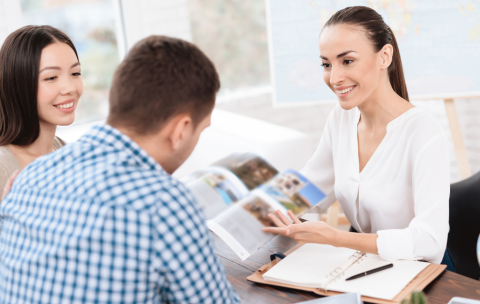 Young-couple-in-a-travel-agency-being-shown-a-brochure-by-the-travel-agent