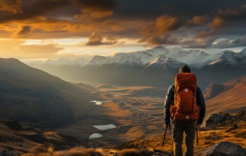 Hiker with backpack and trekking poles in the mountains during sunset